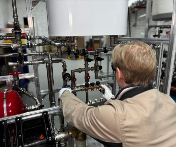Installateur arbeitet an den Anschlüssen eines Warmwasserboilers