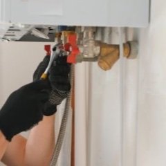 Hände arbeiten an den Anschlüssen einer Gastherme